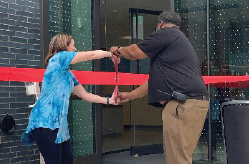 Ribbon cut: Radnor Associate Executive Director Tracey Commack and Facilities Director Neal Ali use giant ceremonial scissors to cut a red ribbon.